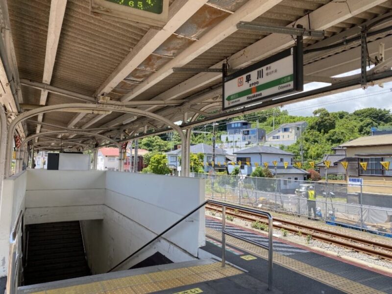 早川駅のホームから階段を見上げた写真 周囲には住宅と線路がある